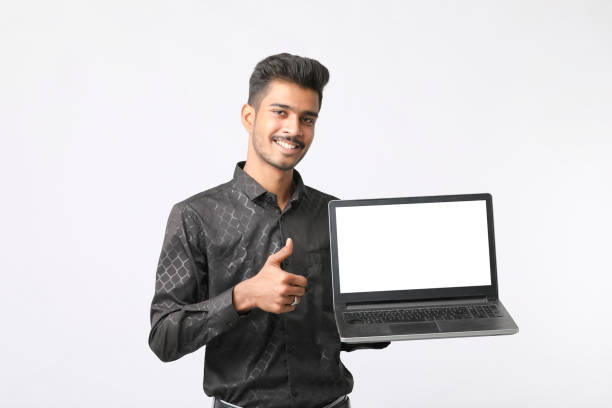 istock Young indian man showing laptop screen on white background. 1388499882
