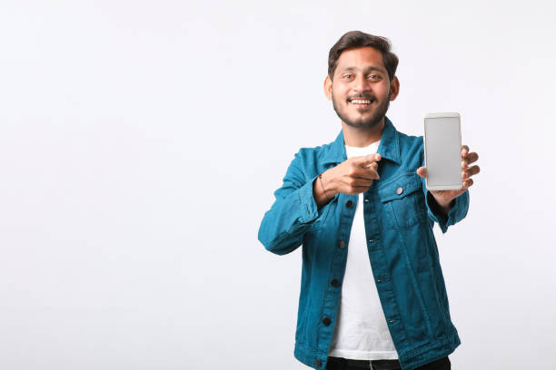 giovane indiano che mostra lo schermo dello smartphone su sfondo bianco. - thumps up foto e immagini stock