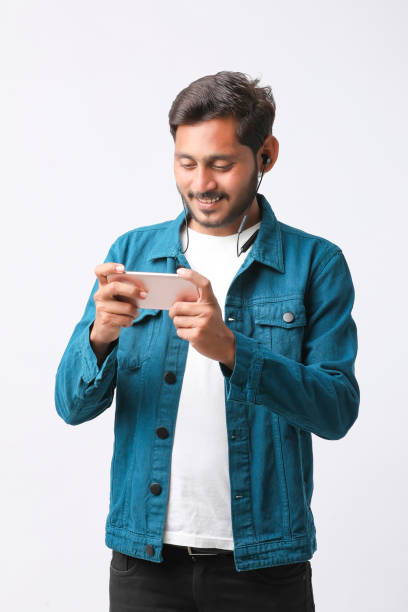 istock Young indian man using smartphone and giving expression on white background. 1388499998