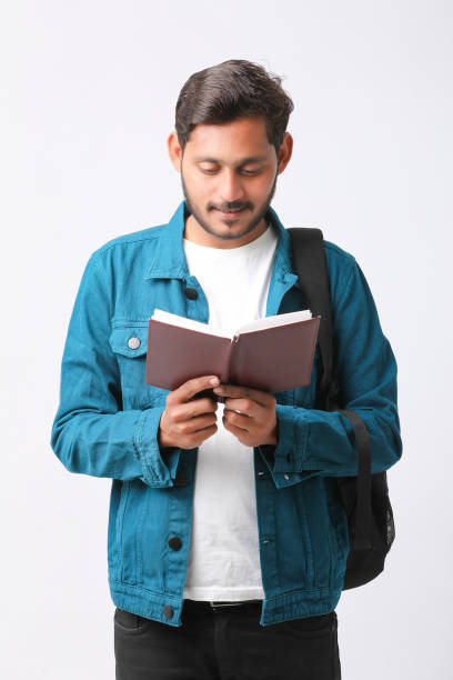 istock Young Indian college student holding diary in hand on white background. 1388500007