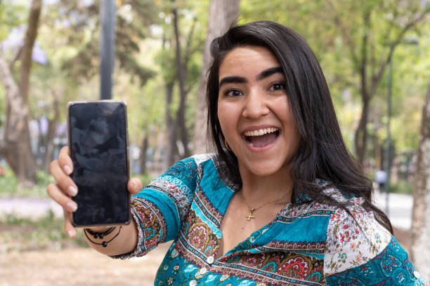istock Woman using her cellphone in a park 1388504240