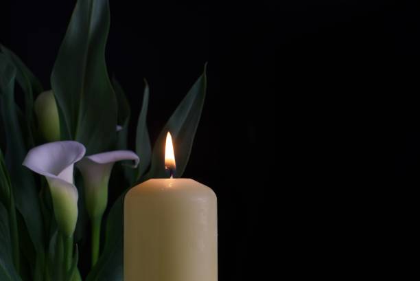 istock Candle burning flame in the darkness and arum lilies 1388504924