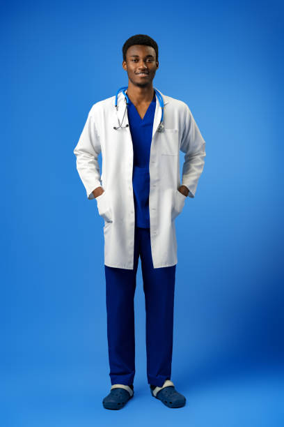istock Confident black doctor posing over blue studio background. 1388507556