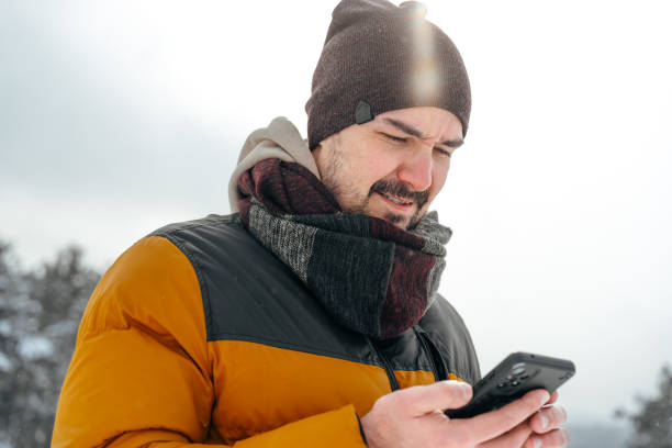 istock Young man in snowy winter forest using cell phone 1388507726