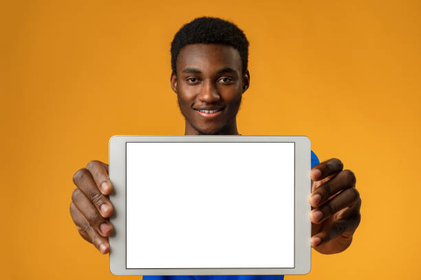 istock African american man showing blank digital tablet screen with copy space in yellow studio. 1388507919