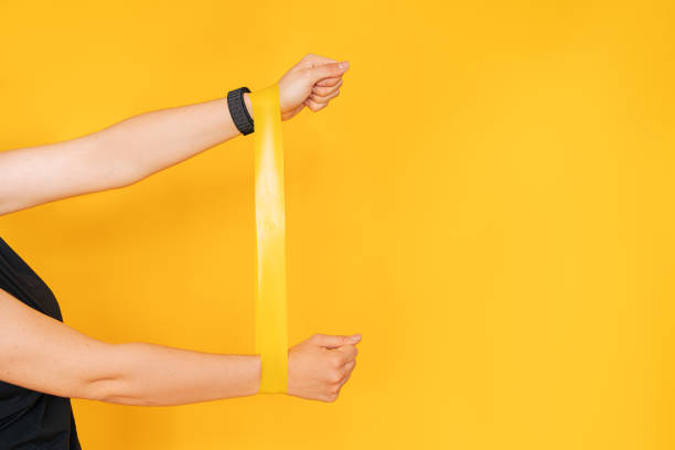 istock Girl with hands stretching rubber band against yellow background 1388510017
