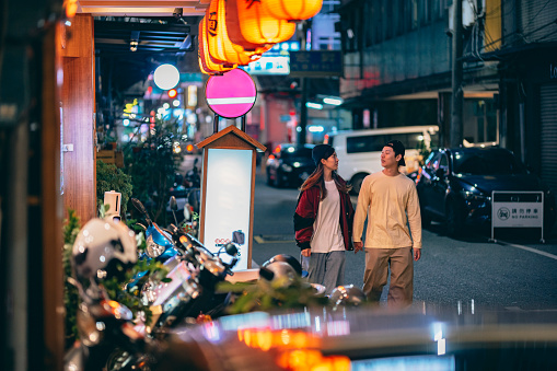 An asian couple walking on the street at night in Taiwan