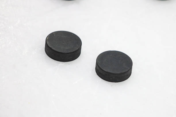 istock Two black pucks laying on ice hockey rink. 1388513253