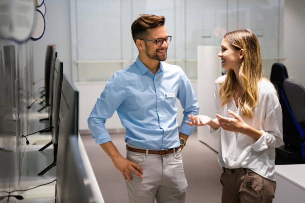 istock Happy people in consumer electronics retail store looking at new digital device 1388514177
