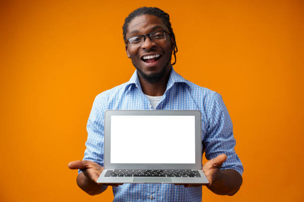 istock Young smiling african man standing and using laptop computer over yellow background 1388515762