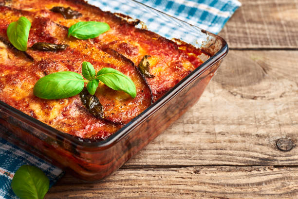 Eggplant parmigiana on rustic wooden table. Italian traditional eggplant parmigiana pie with fresh basil and mozzarella cheese. Homemade eggplant parmigiana. aubergine stock pictures, royalty-free photos & images