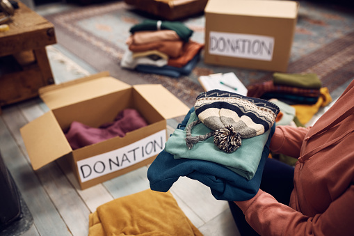 Close-up of woman packing boxes while donating her wardrobe for charity.