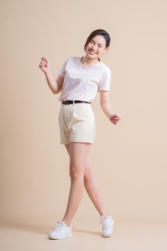 Full length image of young Asian woman posing on background