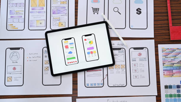 istock Web designer workplace with digital tablet and wireframe sketches of screens for mobile application. 1388520881