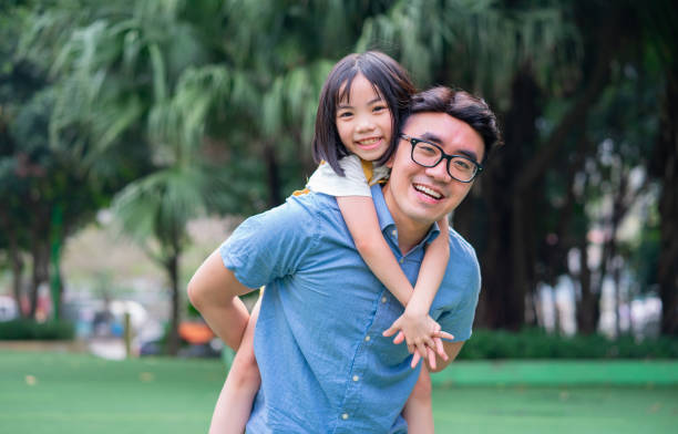 obraz azjatyckiego ojca i córki bawiących się razem w parku - chińczyk zdjęcia i obrazy z banku zdjęć