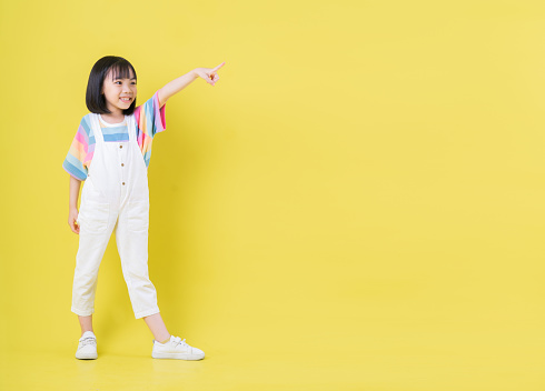 Full length image of Asian child posing on yellow background