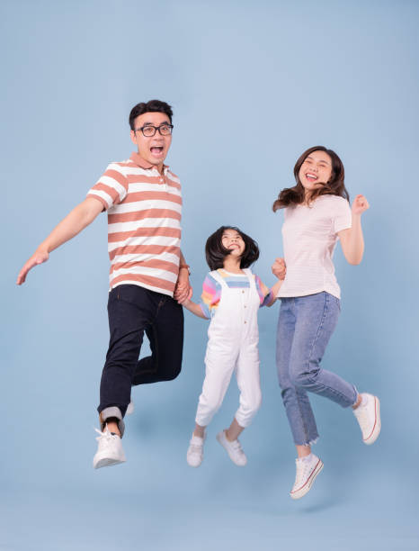 背景にアジアの若者の家族のフルレングス画像 - jump for joy ストックフォトと画像