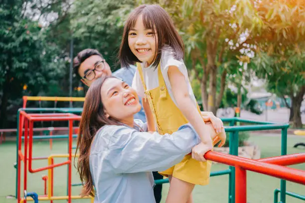 Photo of Image of young Asian family playing together at park