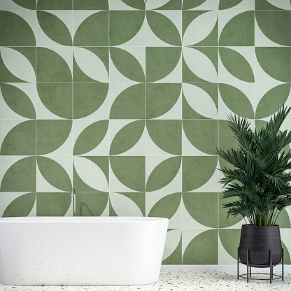 Luxury modern bathroom interior with a self-standing bathtub and potted plant (howea forsteriana) on terrazzo floor, in front of an empty white and khaki green geometric shape tiled wall background with copy space. 3D rendered retro 80's style image.