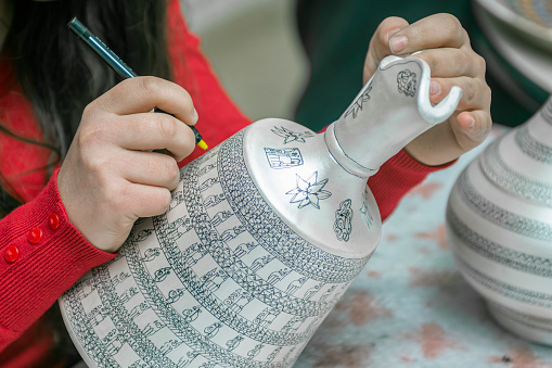 A woman is decorating a pottery as a hobby in Turkey