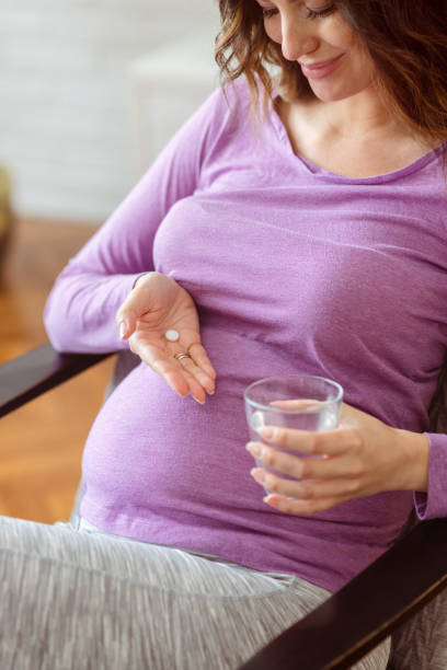 istock Pregnant woman taking pill at home 1388529533