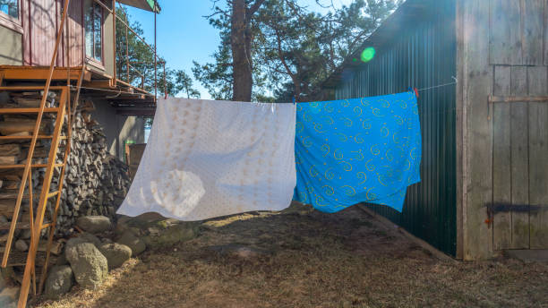 istock Bedding sheets drying on the clothesline outside. Lens flare. Bed linen drying on a clothes line in the garden. 1388534053
