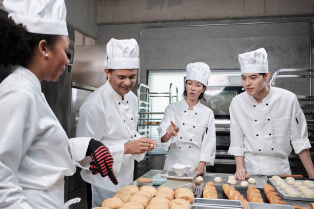 istock Chefs team in uniforms prepare to bake bread and pastry in stainless kitchen. 1388536639