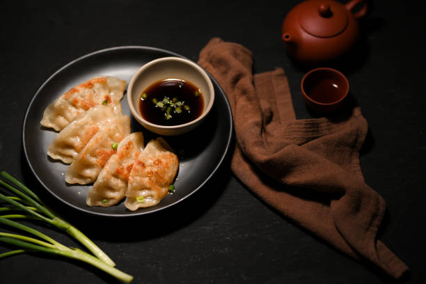 Asian Chinese appetiser, Fried gyoza or fried dumplings Asian Chinese appetiser, Fried gyoza or fried dumplings on a black table background. closeup image appetiser stock pictures, royalty-free photos & images