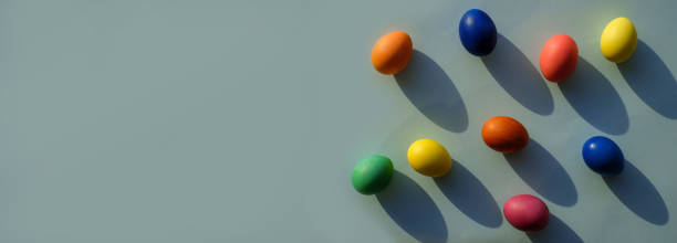 istock Easter eggs on blue background, with sunlight and shadows, top view, banner with copy space 1388541506