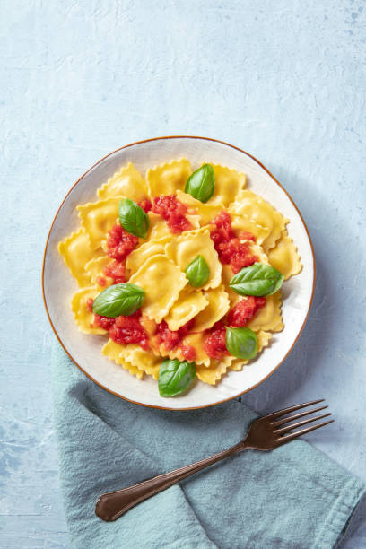 Ravioli with tomato sauce and fresh basil leaves, shot from above stock photo
