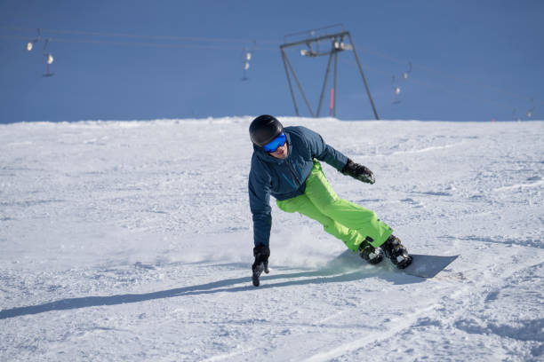 istock Man carves down ski slope, on snowboard 1388543118