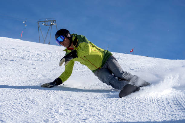 istock Man carves down ski slope, on snowboard 1388543832