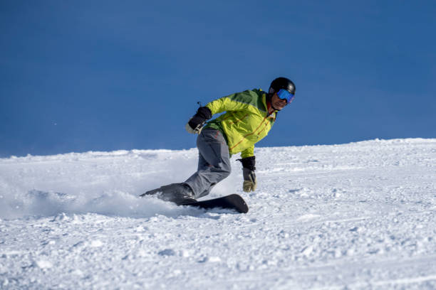istock Man carves down ski slope, on snowboard 1388543836