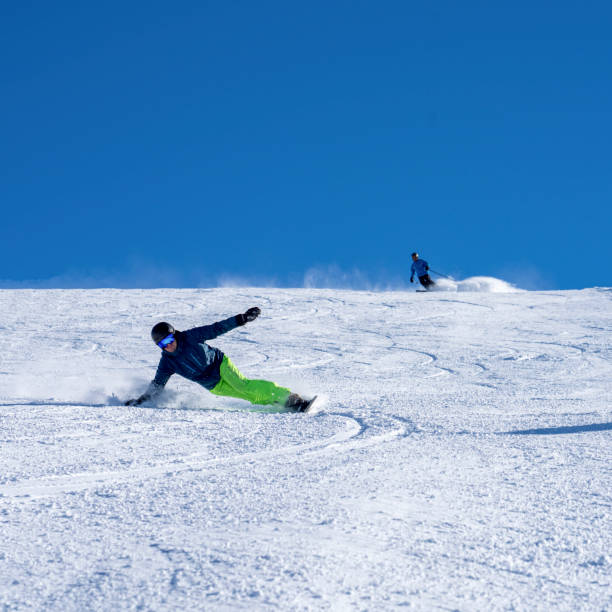 istock Man carves down ski slope, on snowboard 1388544280