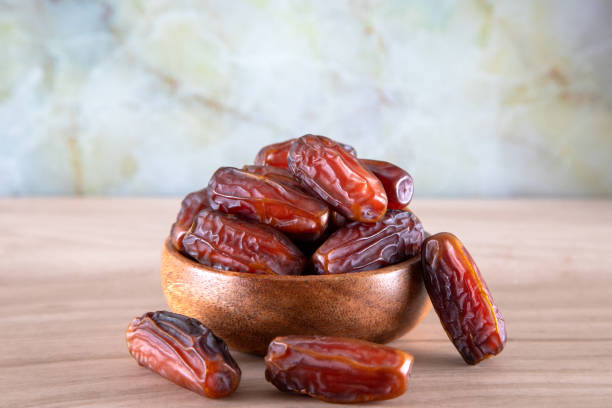 istock Bowl of dates fruit on wooden background 1388545272
