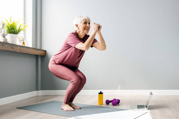 I feel fresh and ready for the day Full length view of an active woman in her 60s working out and doing some squats at home exercising photos stock pictures, royalty-free photos & images