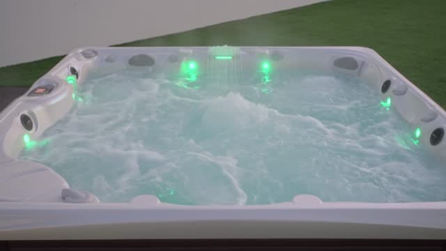 Close-up of the surface of a modern hot tub for relaxation therapy and rehabilitation in a hotel. Bubbles of water in a bath under oxygen pressure In evening outside with lights