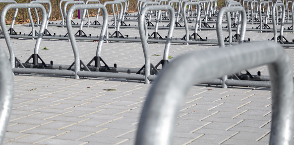 Close ups of a group of modern bike racks in bracket shape on a large public parking area
