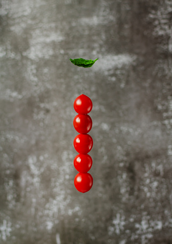 Levitation cherry tomatoes and spinach leave on grey background