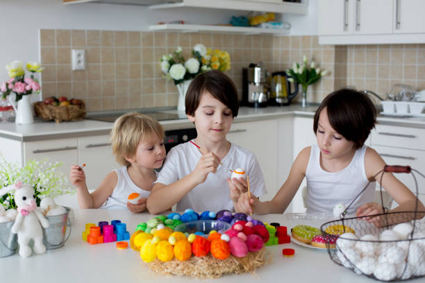 istock Three children, sibling brothers, painting easter eggs for decoration 1388549041