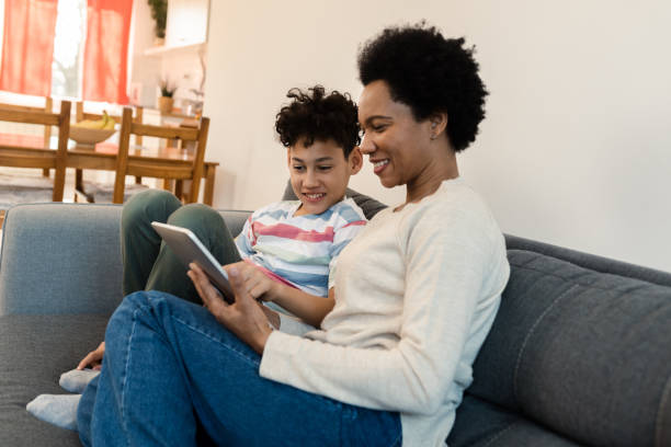 istock Afro woman and her boy watching something fun on tablet 1388551157