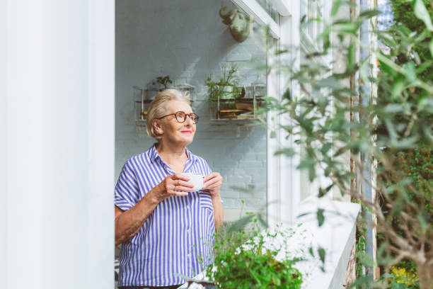 Elderly woman having coffee at window