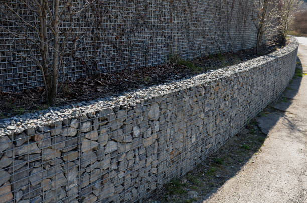 construção de um muro de contenção de gabião, como parte da esgrima casa. trabalhadores colocam geoestextos e sobre ele cestas de arame que consiste em pedras de granito. exigindo trabalho manual - controla da erosão - fotografias e filmes do acervo