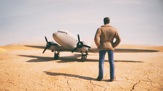 A miniature man in the desert eyes up a DC-3 Dakota aeroplane. Scale model photography.