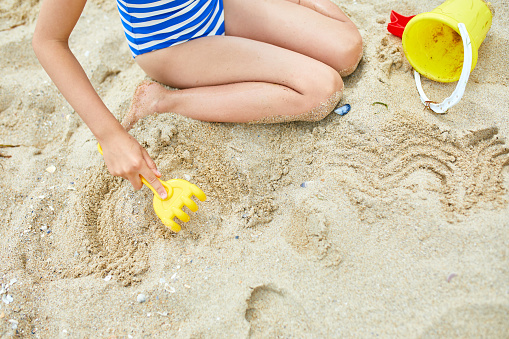 Little girl kid having fun on the beach and playing with sand toys, family summer vacation, Background with empty space for text
