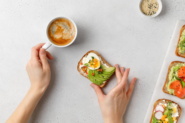 istock Breakfast with coffe and avocado toast. Eating a sandwich with avocado, eggs, micro greens. 1388563081