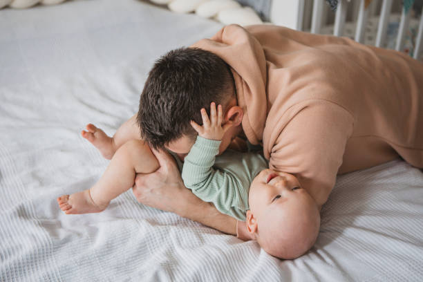 istock Father and baby playing on bed 1388564227
