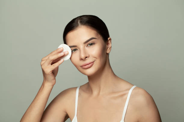 istock Healthy female model removing makeup with cotton pad and smiling 1388564345