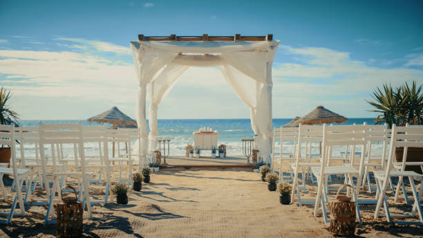 Empty Decorated Outdoors Wedding Venue with Chairs for Official Ceremony on a Beach Near the Sea or Ocean. Everything Prepared for Beautiful Romantic Marriage Celebrations. Guests are Arriving Soon. Empty Decorated Outdoors Wedding Venue with Chairs for Official Ceremony on a Beach Near the Sea or Ocean. Everything Prepared for Beautiful Romantic Marriage Celebrations. Guests are Arriving Soon. altar stock pictures, royalty-free photos & images