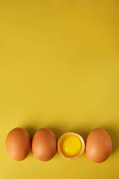 istock Fresh brown eggs and a broken egg with yolk on a light yellow background with space for text, copy space 1388564500